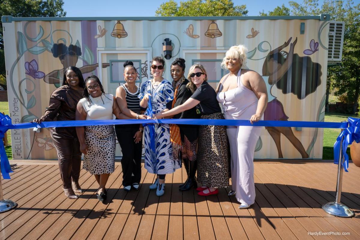 Seven woman posing for a ribbon cutting ceremony