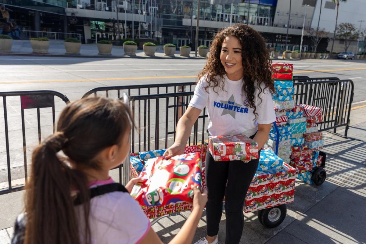 An AEG volunteer hands out gifts to students at AEG's 10th Street Elementary Holiday Party in Los Angeles, CA.
