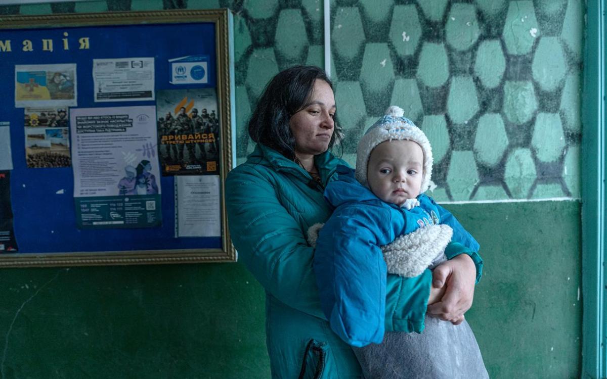 Woman holds baby in clinic with teal walls 