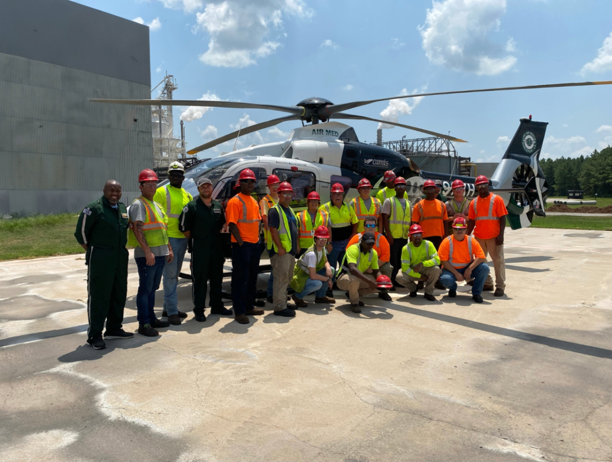 A group of people posing for a photo in front of a helicopter 