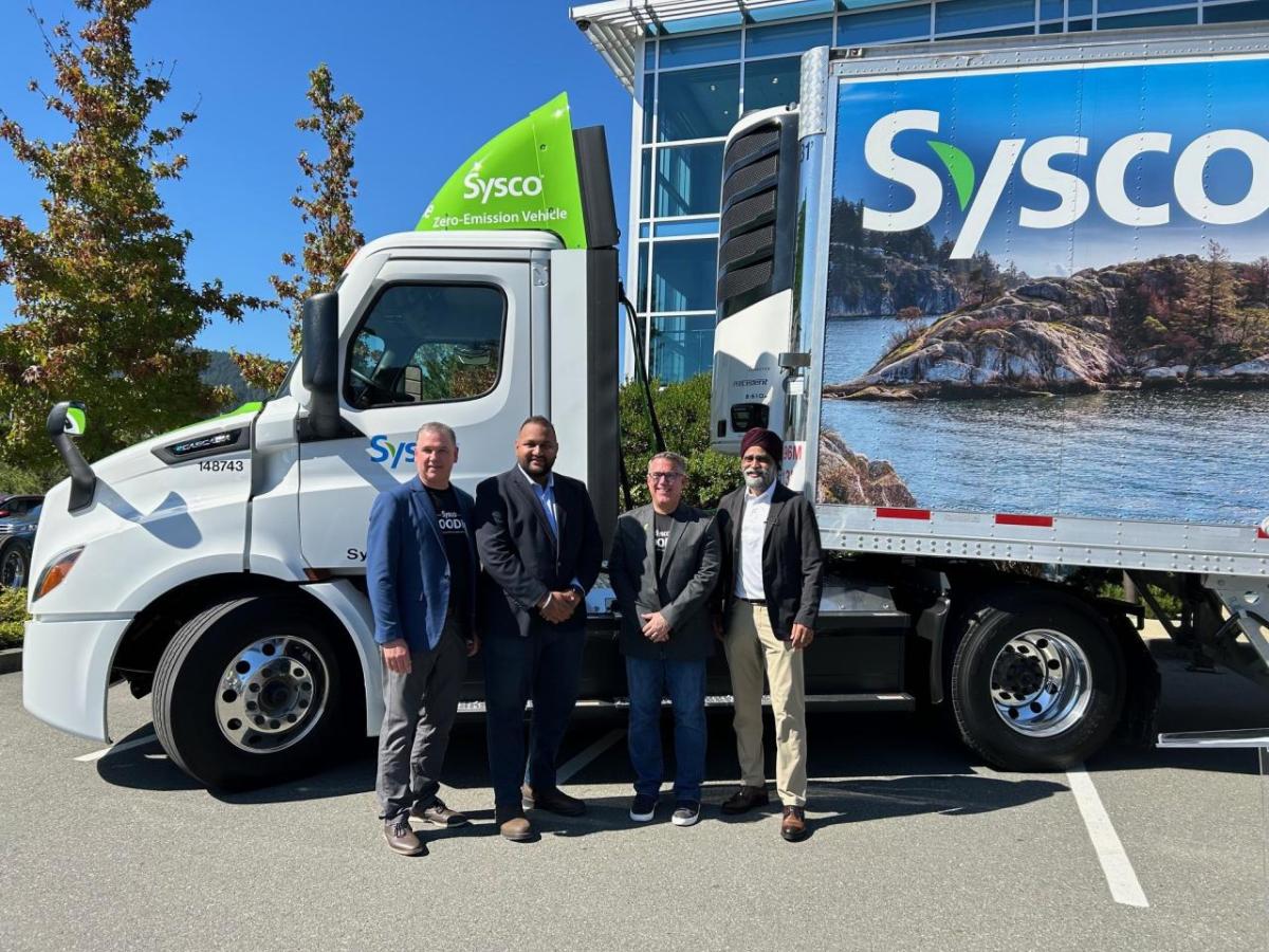 Four people standing by a Sysco semi truck