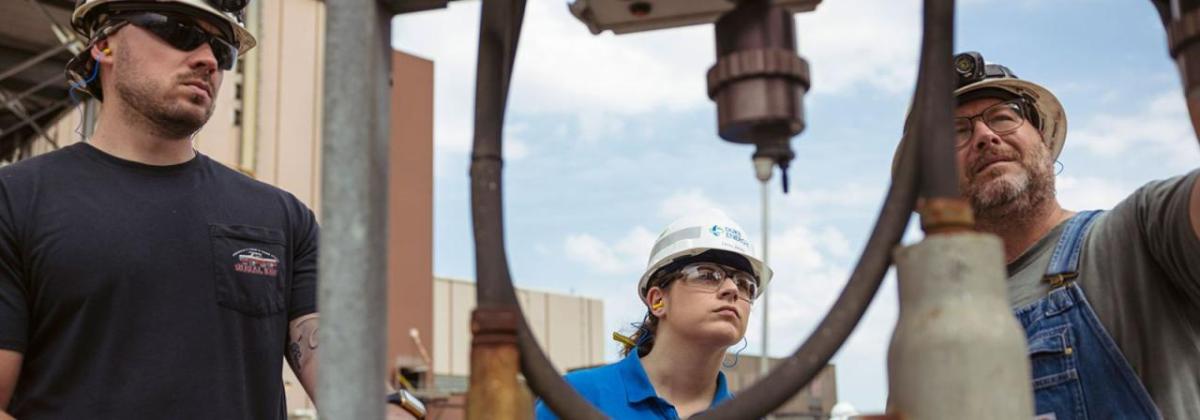 Emily Jones and two others inspecting equipment.