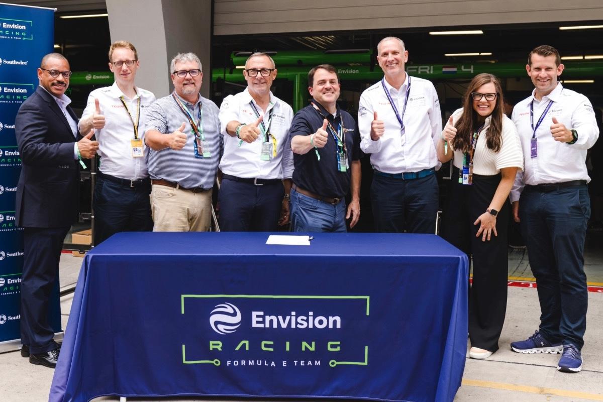 Group standing behind Envision Racing table giving the thumbs up