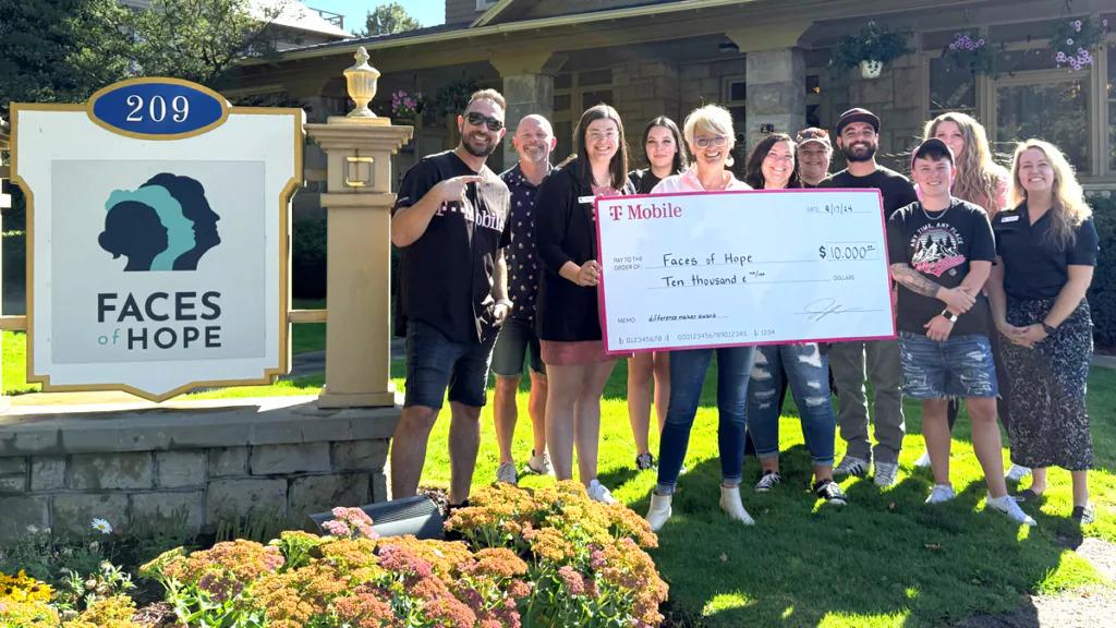 A small group posed with a large check outside a building