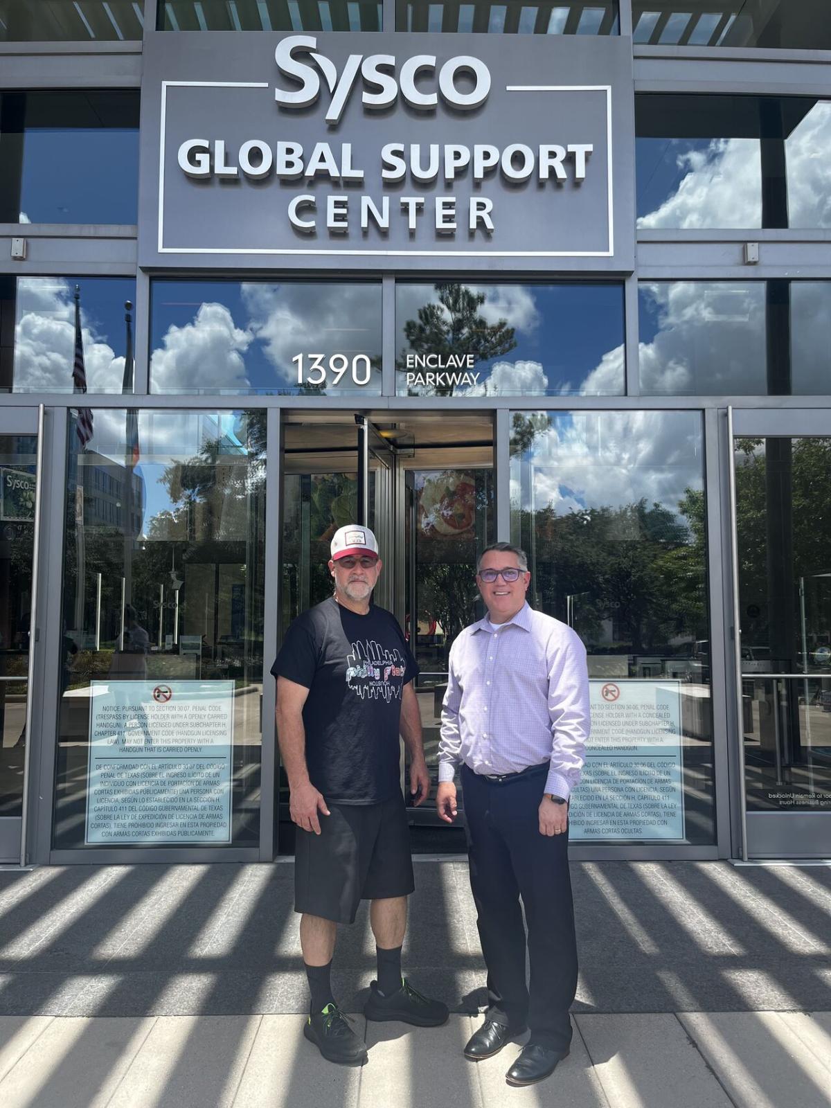 2 people stand together outside the Sysco Global support Center