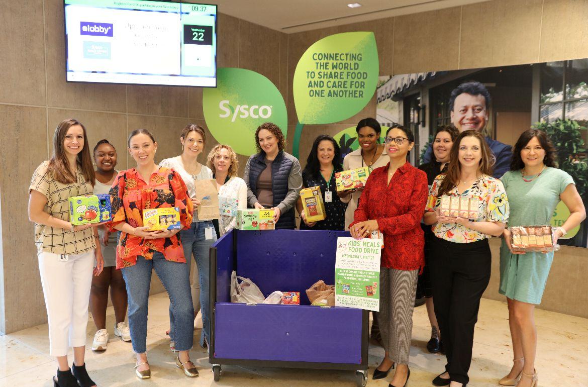 A large group photo of people holding food supplies 