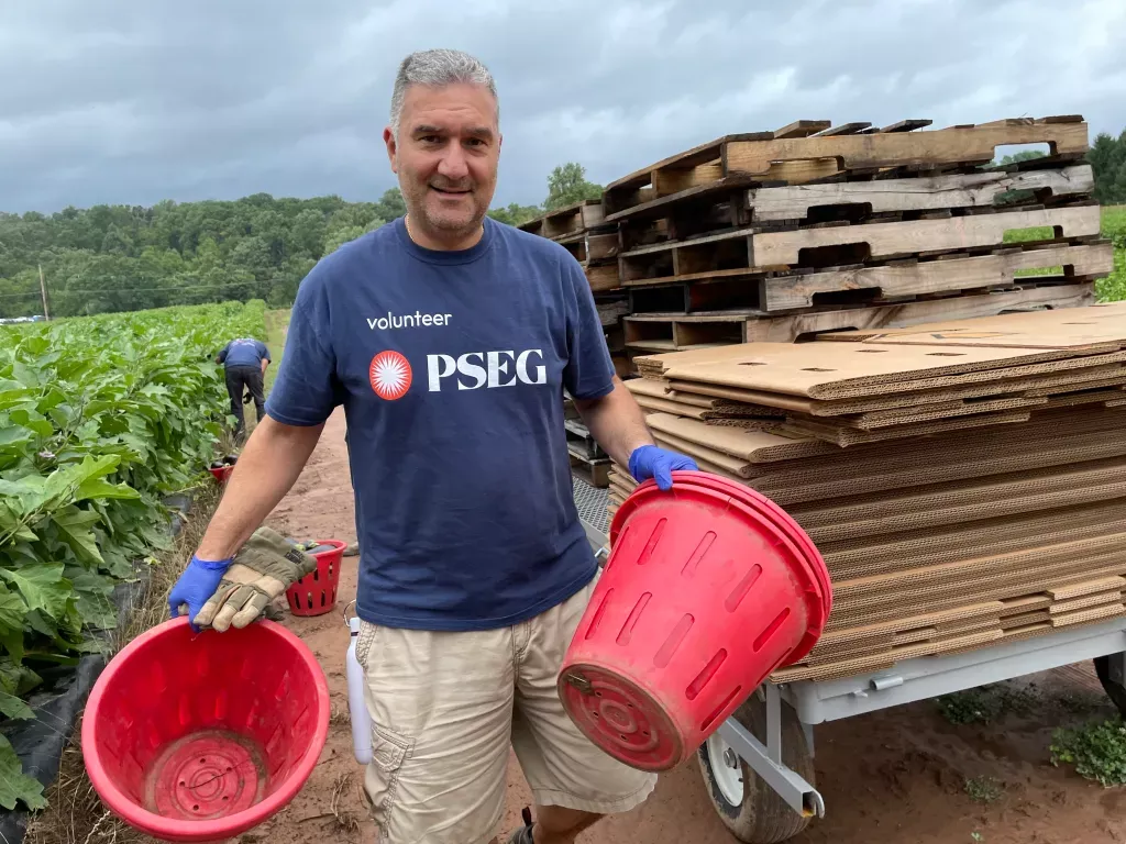 volunteer in PSEG shirt holding red buckets