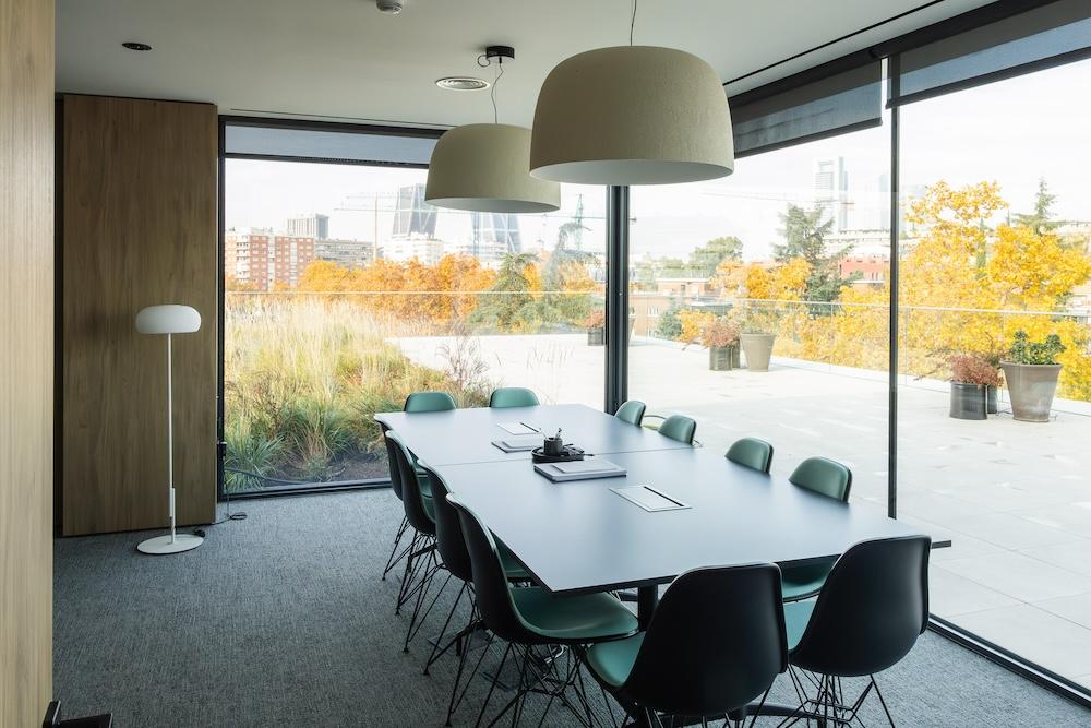 Conference room in modern office building with floor to ceiling windows that look out onto a green space