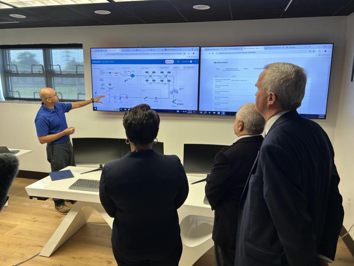 Veolia Project Manager Erick Gomez demonstrates the Hubgrade digital solution in the new control room at New Orleans’ East Bank wastewater treatment plant for, from left to right, New Orleans Mayor LaToya Cantrell, Sewerage and Water Board of New Orleans Executive Director Ghassan Korban and Veolia North America CEO Frédéric Van Heems.