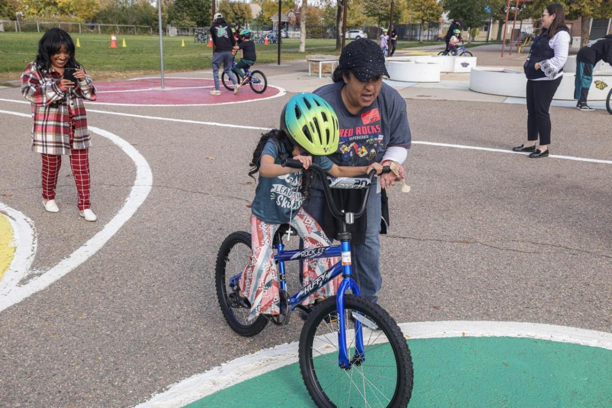 A young girl practiced riding a bike with the help of an AEG employee volunteer. (Photo: Jon Angel)