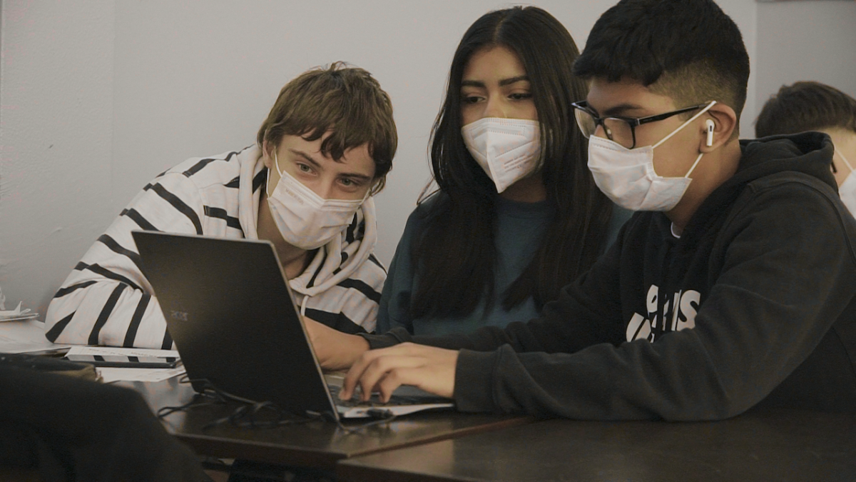Three students using a laptop