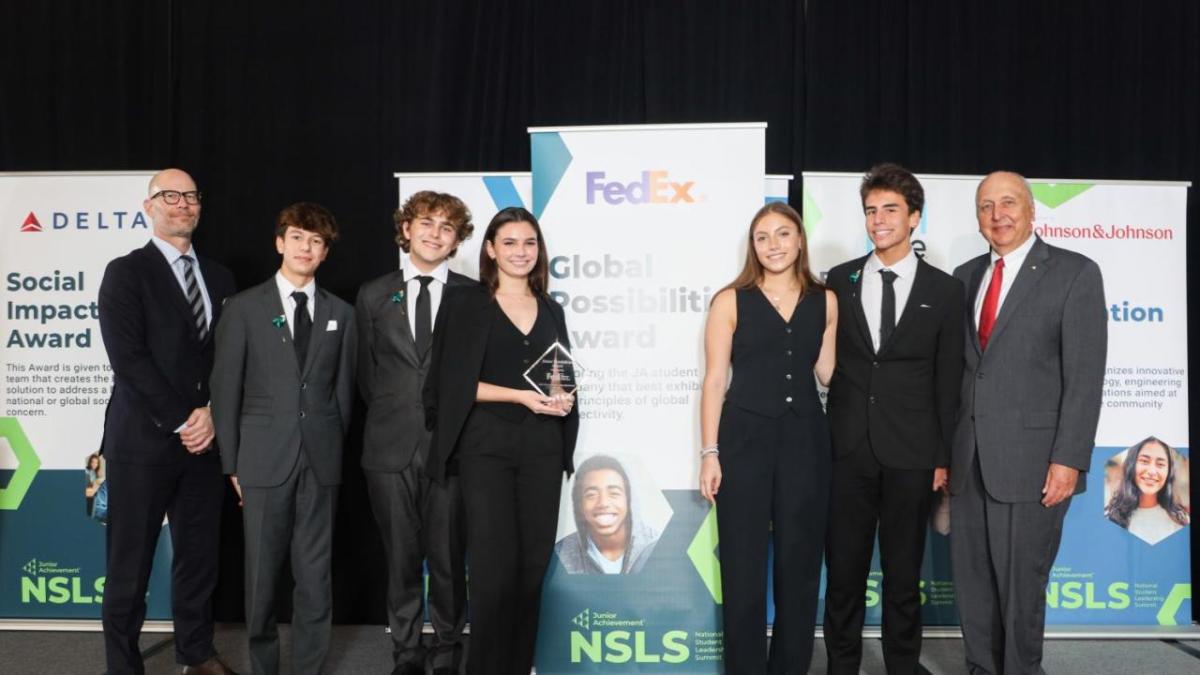 People posed on a stage, one holding an award.