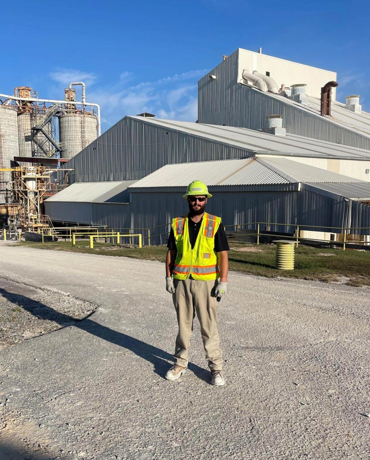 John Hargrove standing outside buildings on a driveway in hard hat and high-vis vest.