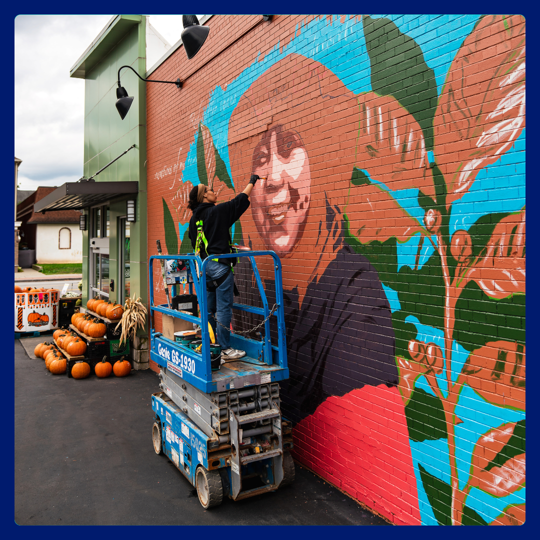 Artist Julia Bottoms paints a mural of Ibu Rahmah, a coffee farmer from Indonesia, outside Lexington Co-Op in Buffalo, NY.