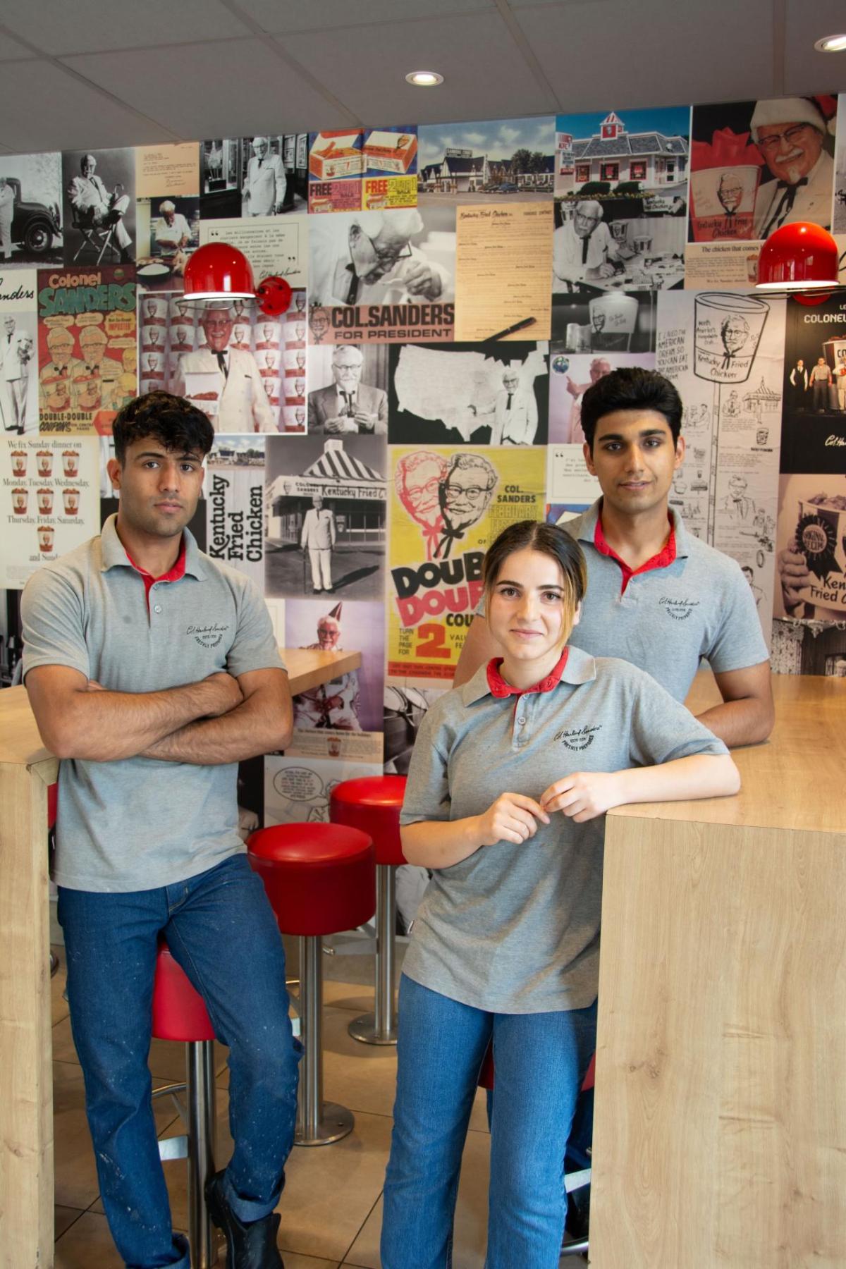 Three people leaning against restaurant tables 