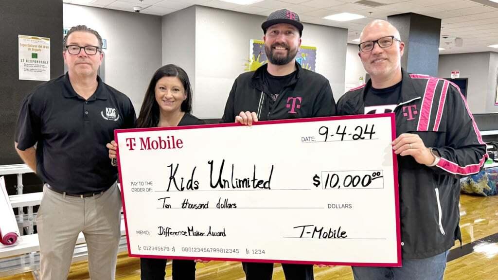 A small group posed with a large check inside a building.