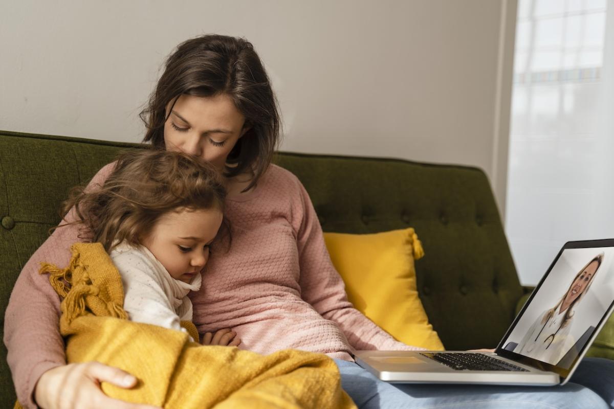 Mom and daughter seated on a couch together.