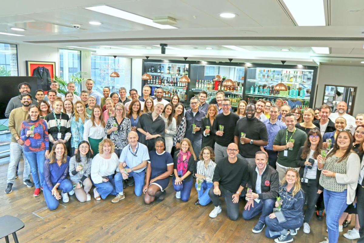 A group of people posed in a room with Bacardi products displayed behind them.