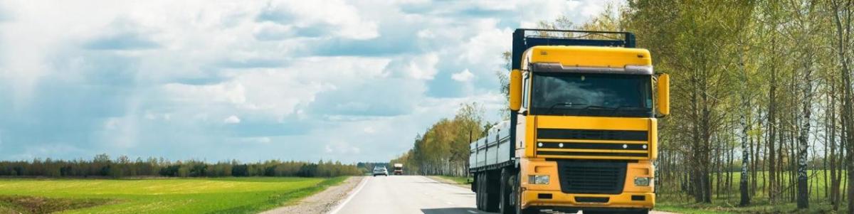 Yellow lorry driving down a road