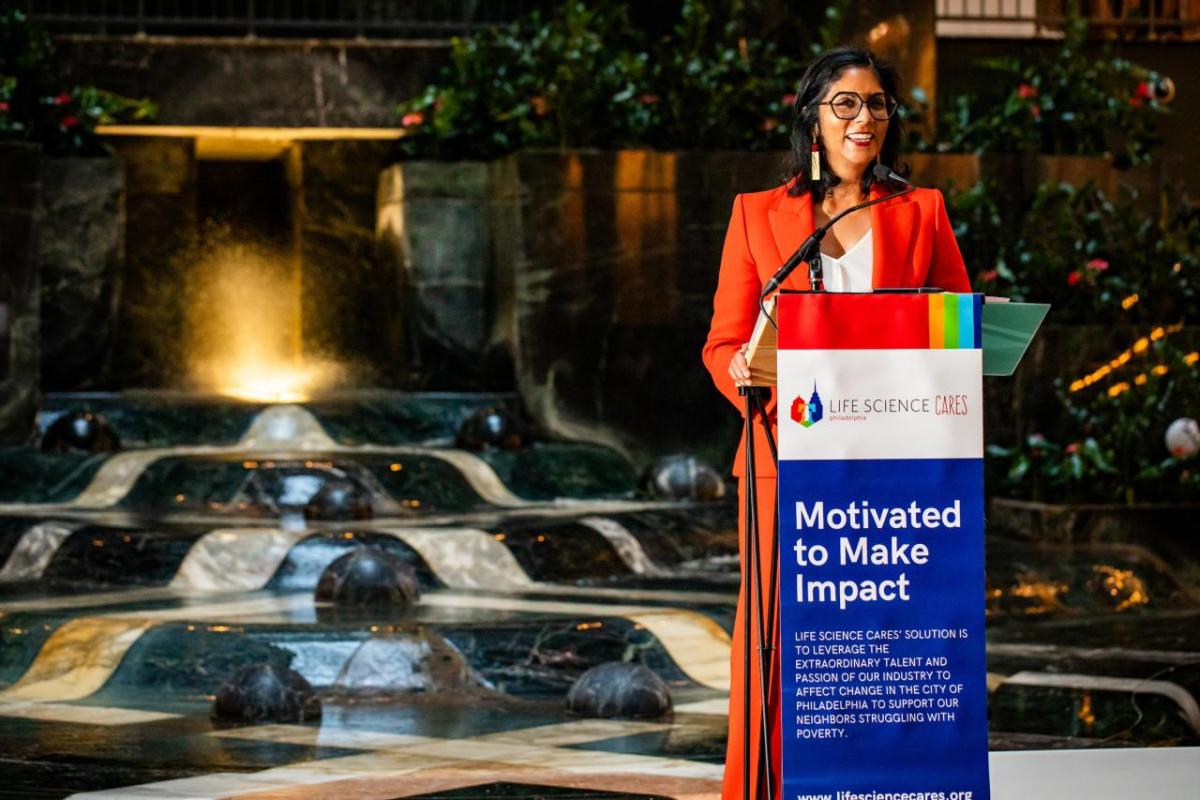 speaker at a lectern with a sign "Motivated to make impact"