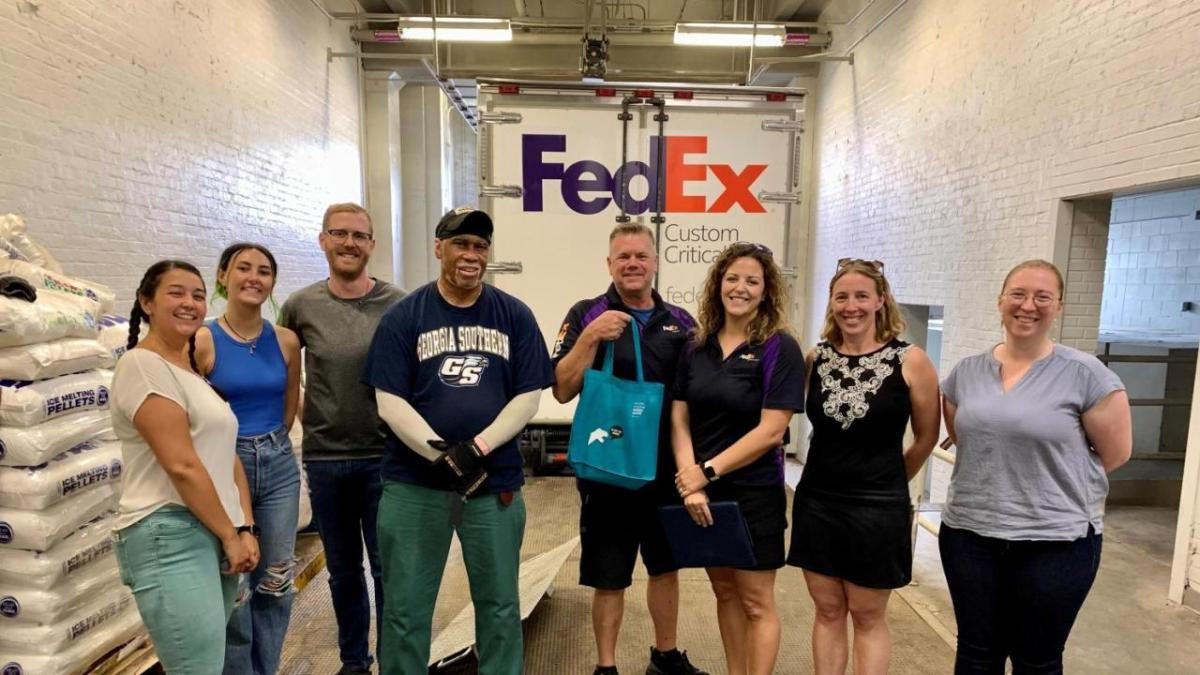 a group standing in front of a FedEx truck