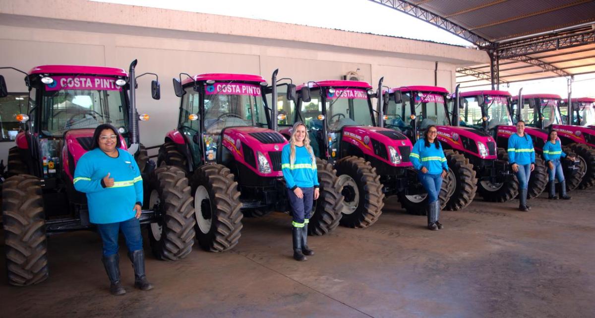 Women stood in a line in front of pink tractors 