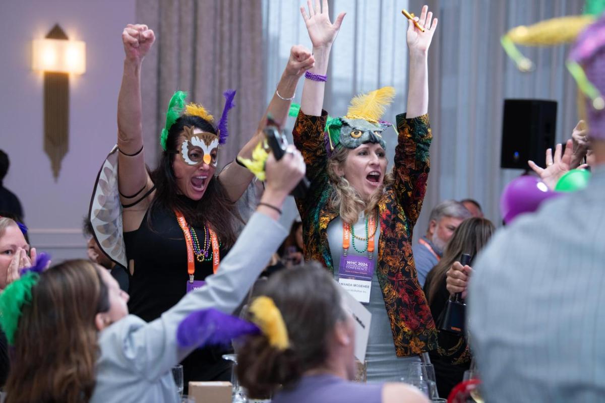 Conference attendees celebrating while wearing Mardi Gras themed hats
