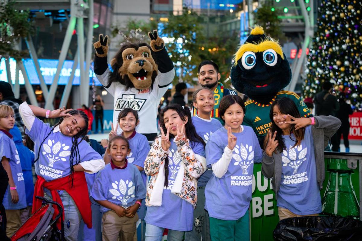 Children pose with LA Kings mascot Bailey and LA Galaxy mascot Cozmo at AEG's community holiday party at Peacock Theater at L.A. LIVE.