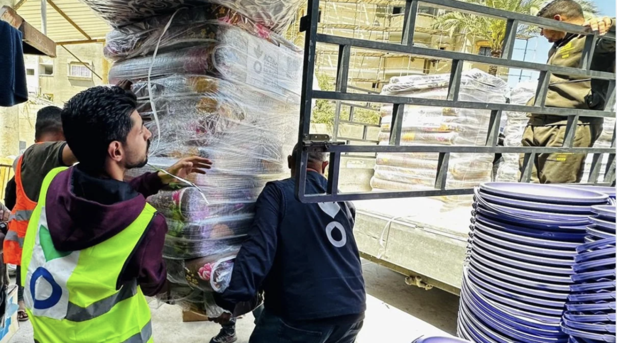 Three people moving heavy supplies onto a truck