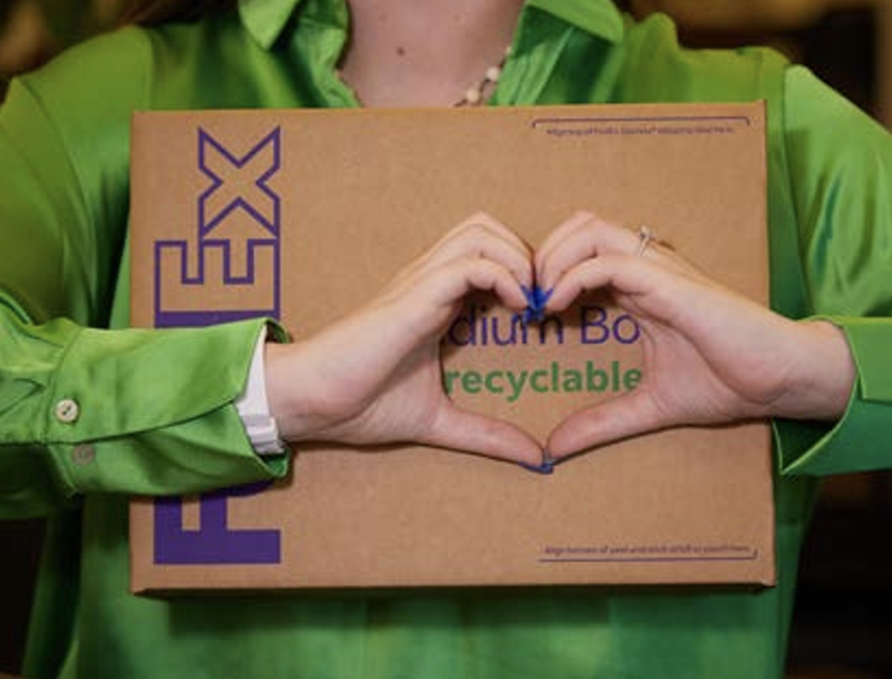 Person making a heart with their hands over a FedEx box