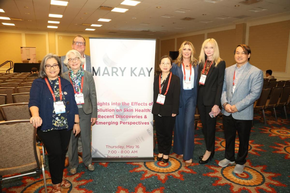 A group posed by a sign "Mary Kay" in a conference room.