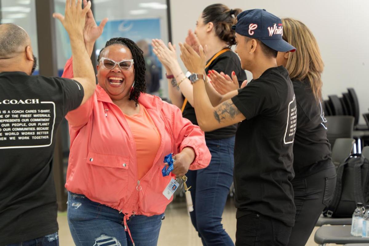 A smiling woman high-fives a Coach volunteer