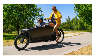 A person riding a bike with a child in a carrier in front.
