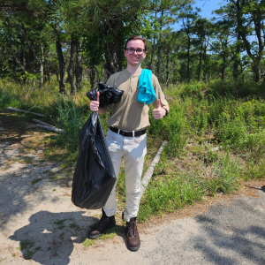 Mathew Sweeney posed holding a trash bag outside.