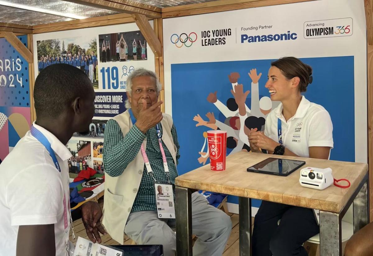 Three people sat around a table talking to each other 