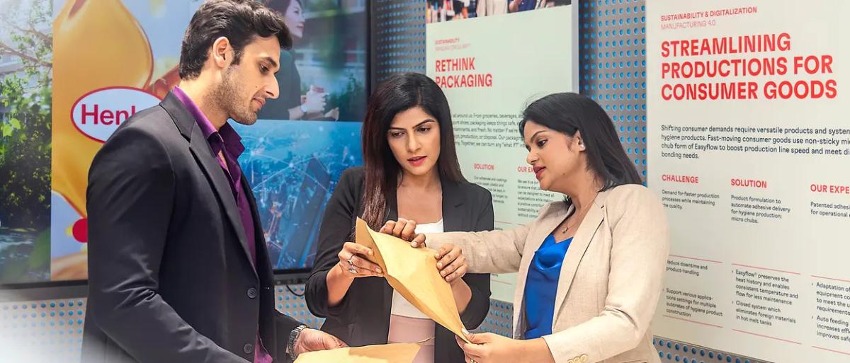 Three people talking, looking at documents