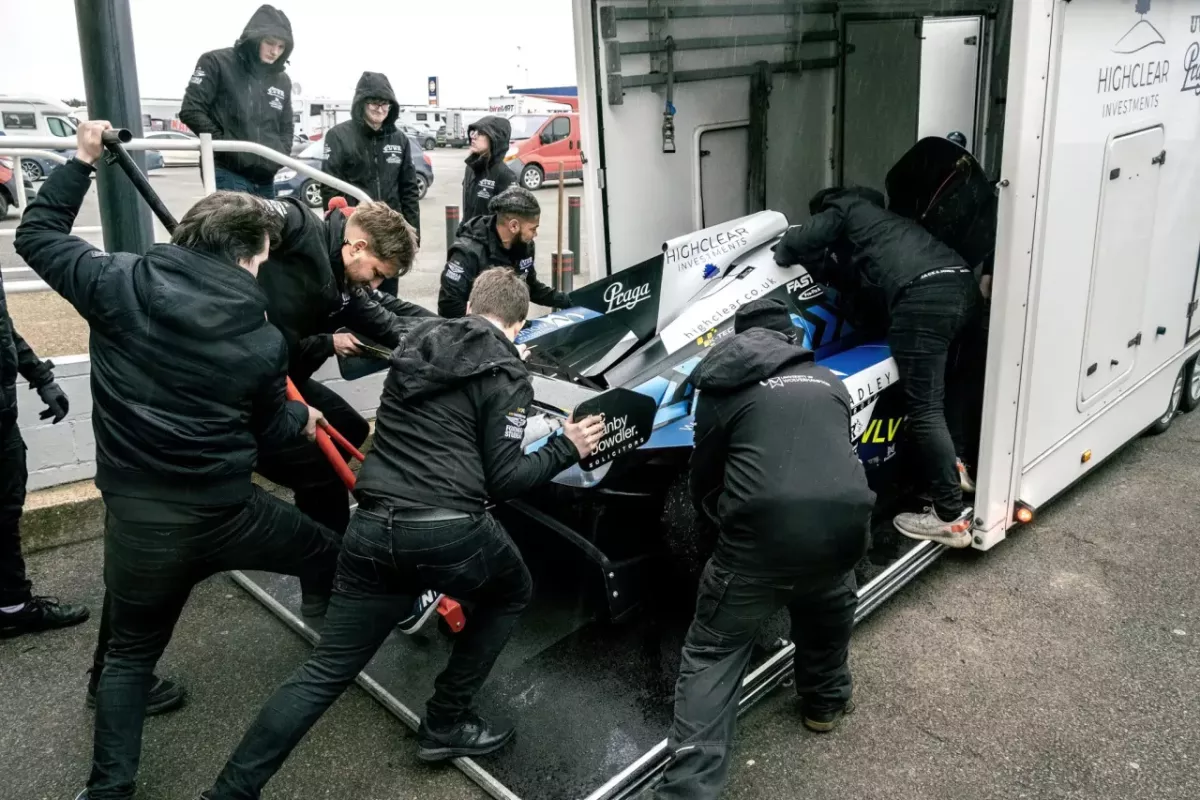 People helping push a motorsport car into a lorry