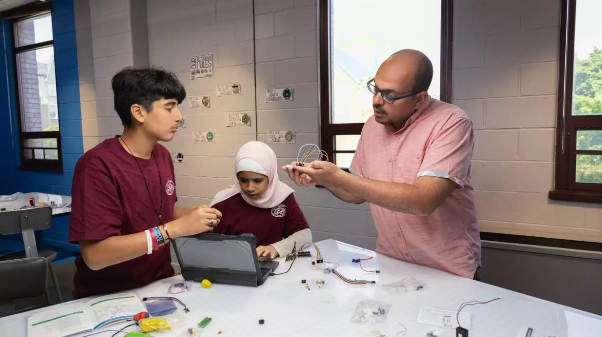 2 students and a teacher work on a project