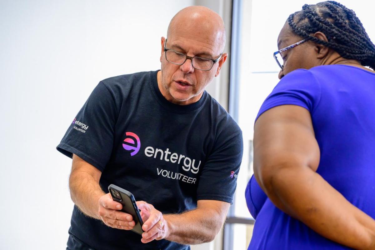 An Entergy volunteer showing another person something on a mobile device