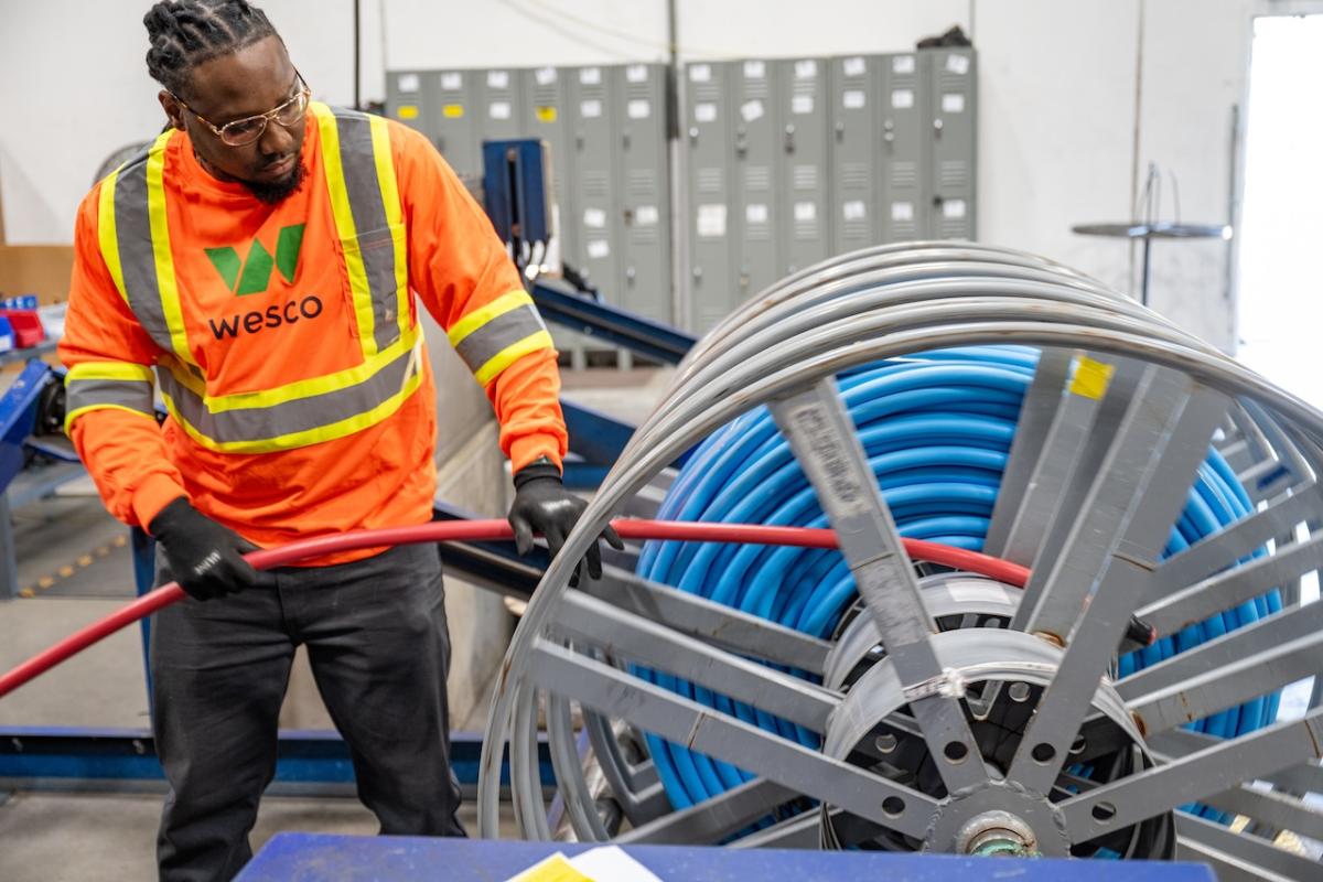 Wesco employee in safety gear reeling in a cable.