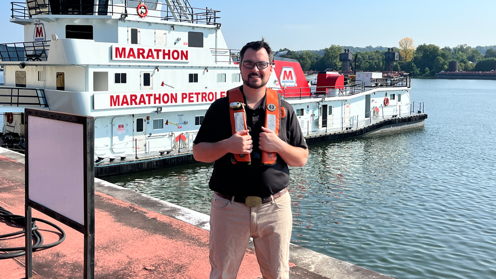 Wesley Rhoden wearing a life vest standing on a pier, a Marathon boat behind them.