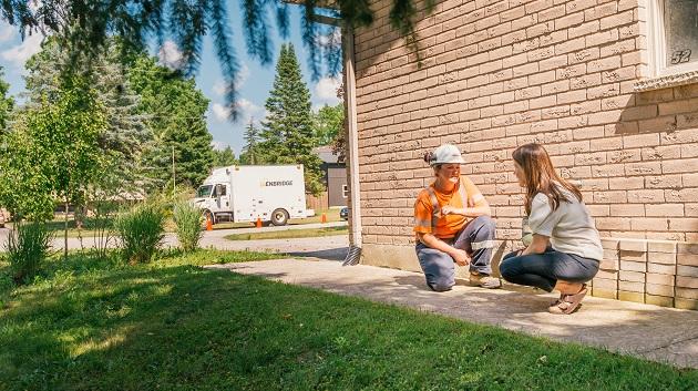 utility worker and homeowner crouched near a home and talking