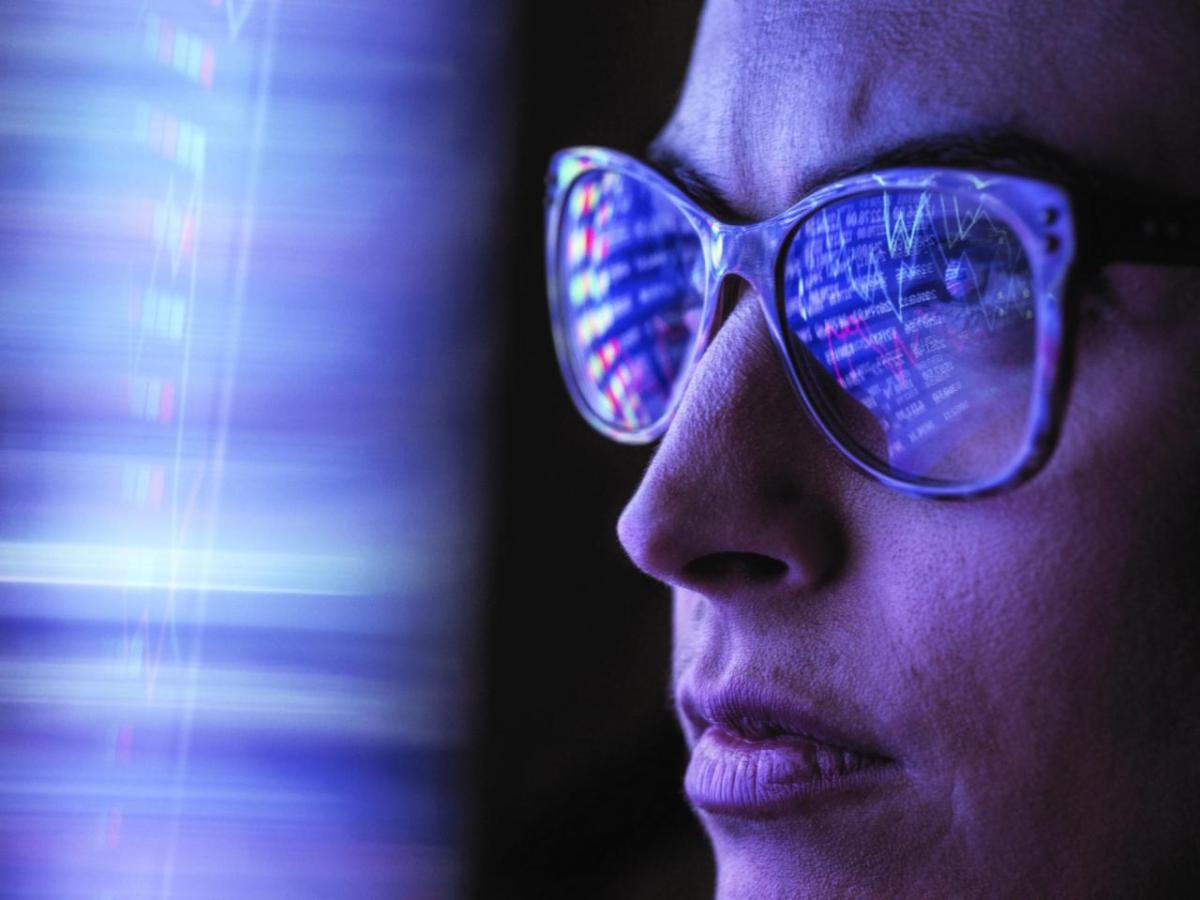 Person in front of blue digital light with reflection on their glasses