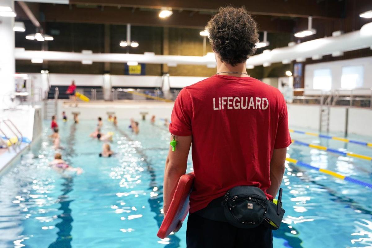 A life guard looking out over a large indoor pool with swimmers.