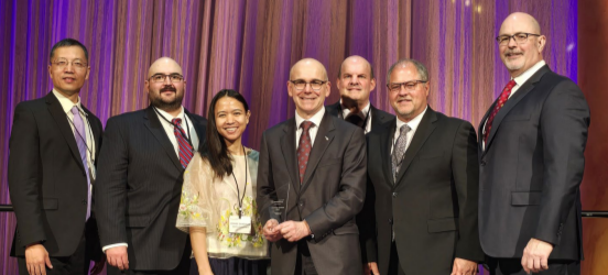 A group posed, one holding an award.