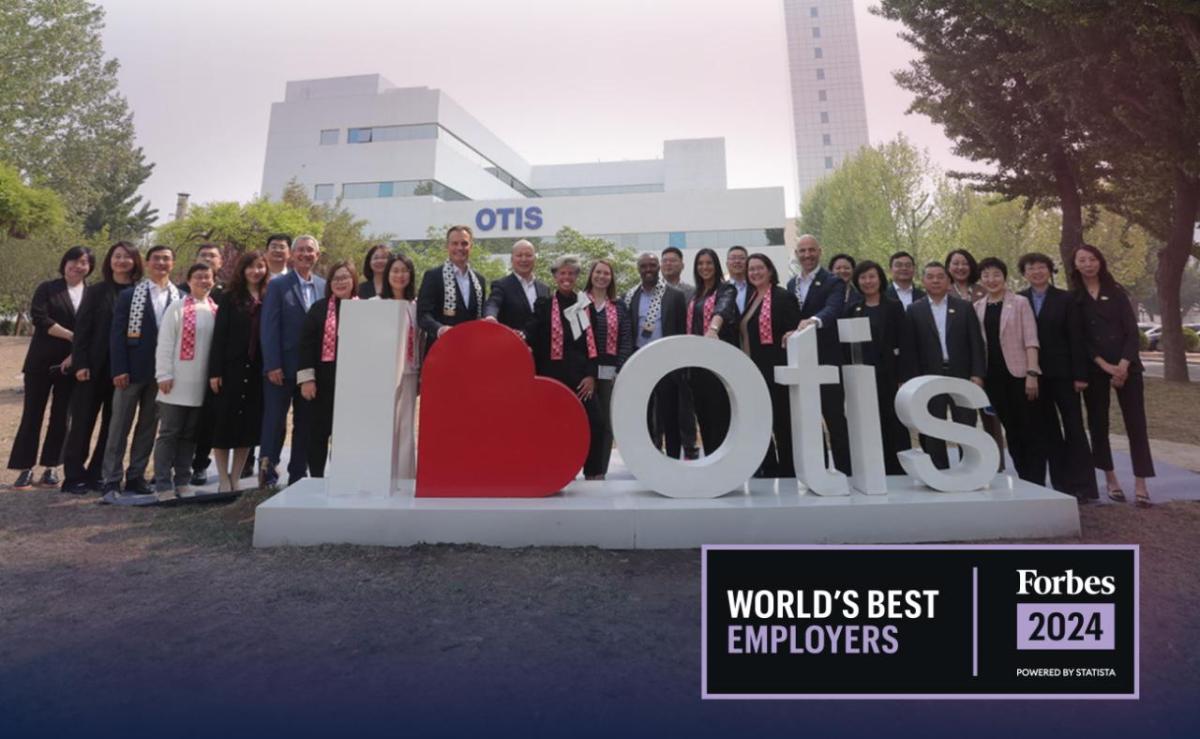 A large group posed outtside, behind a "I 'heart' Otis" sign. Forbes 2024 World's Best Employers logo in the corner.