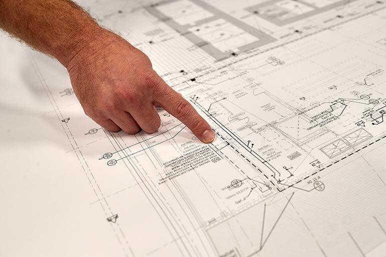 A person pointing to a spot on a building plan.