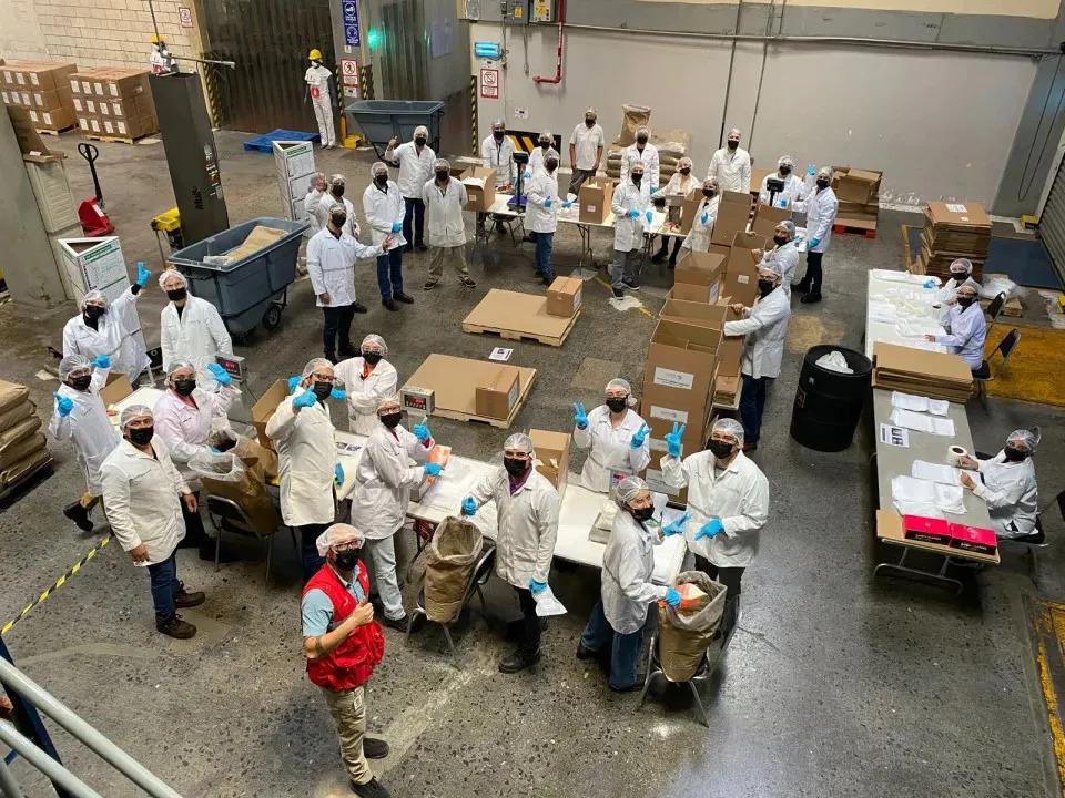 Aerial view of volunteers in protective coverings, working with boxes and food in a warehouse setting.