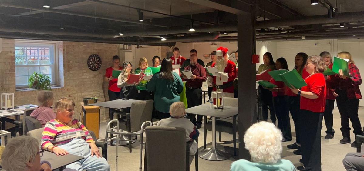 A group singing to others seated.