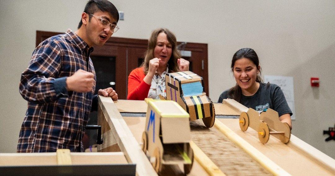 People racing small cars made out of cardboard 